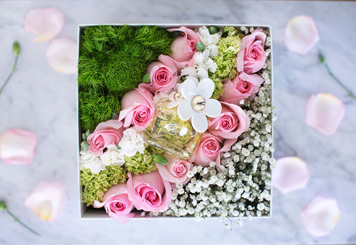 Идеальное решение для весеннего подарка: благоухающие розы в шляпной коробке с зеленью, гипсофилой и живой травой для декорирования.